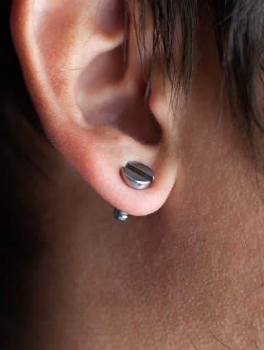 piercing in a man's ears closeup,ear tunnel.